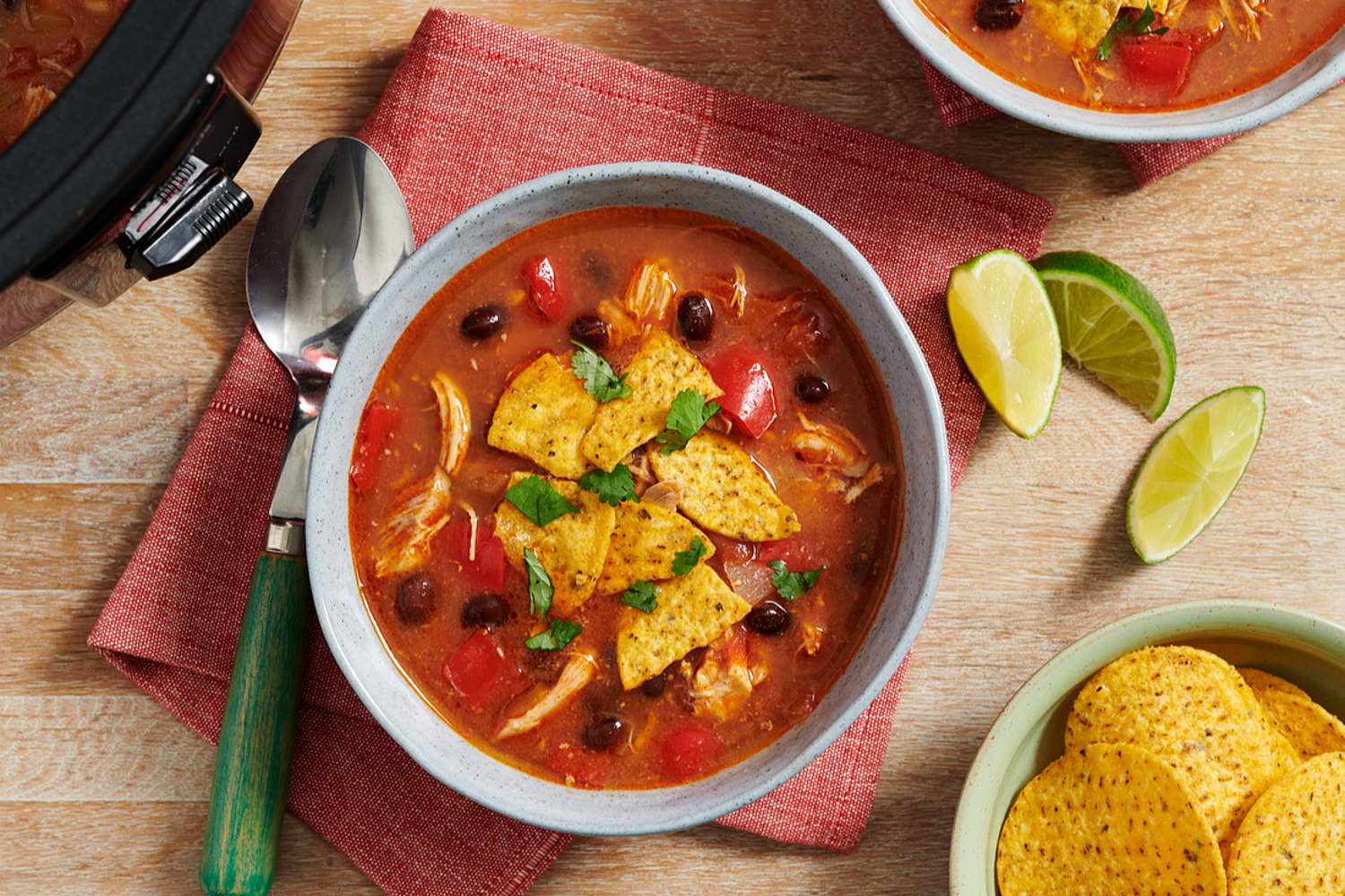 Tomato based soup with visible black beans, chicken, tomatoes and chips as tortilla topping